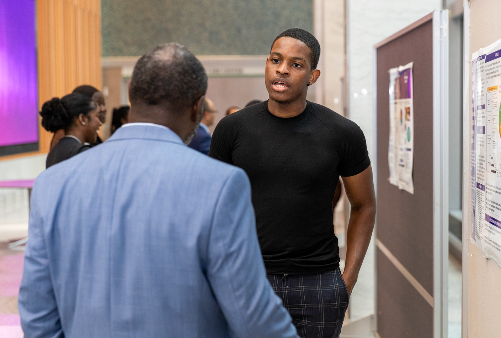 Emeryc Sogbossi speaking with event attendee about the research on their poster